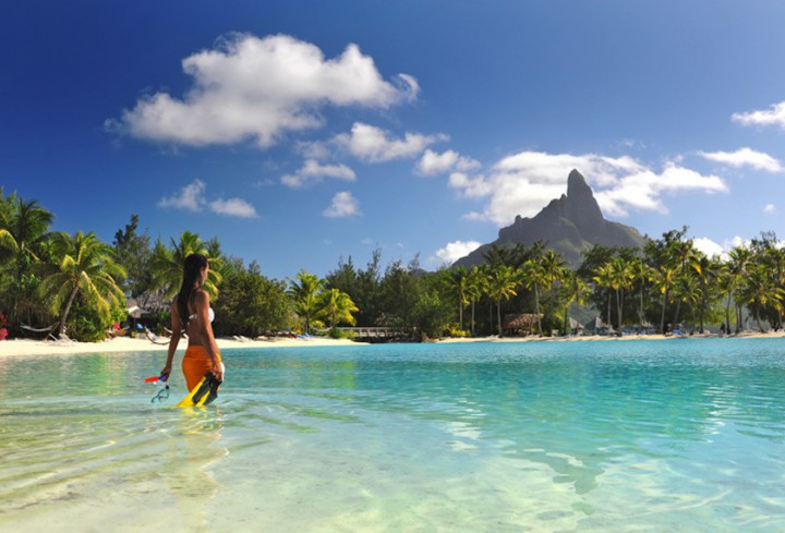 Femme entrant dans la lagune intérieure de l'hôtel Le Méridien Bora Bora face au mont Otemanu
